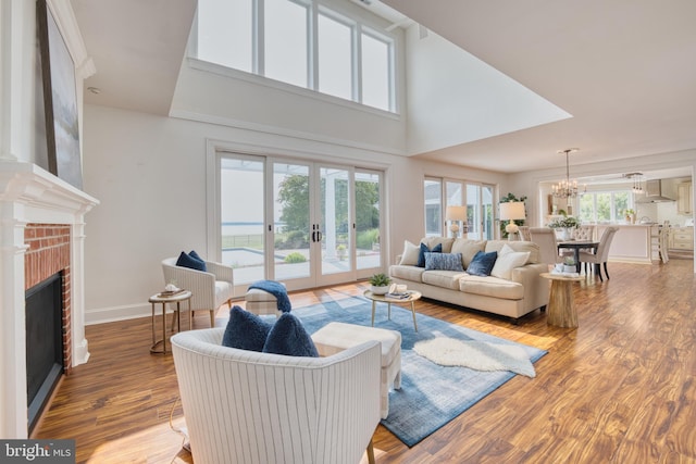 6153 Long Point Rd, Neavitt, MD 21652 - living area with a chandelier, wood finished floors, a brick fireplace, french doors, and a high ceiling