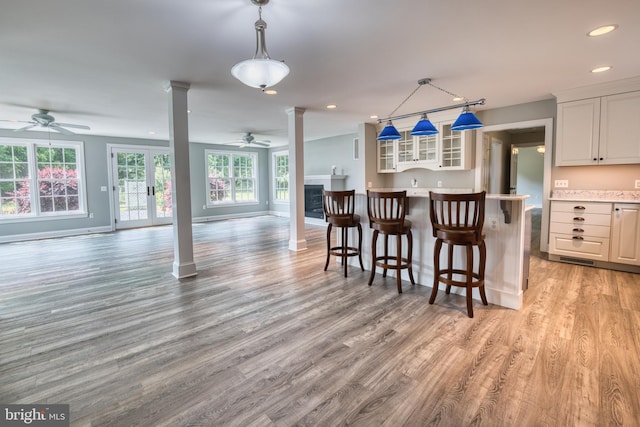 6153 Long Point Rd, Neavitt, MD 21652 - kitchen featuring a ceiling fan, decorative columns, open floor plan, glass insert cabinets, and light wood-style floors