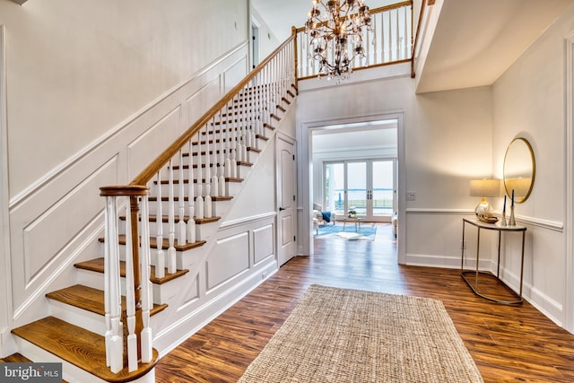6153 Long Point Rd, Neavitt, MD 21652 - stairway with a decorative wall, a chandelier, wood finished floors, a towering ceiling, and french doors
