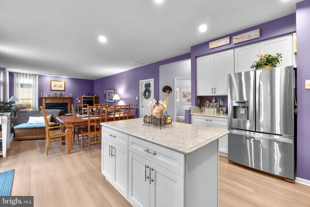 5631 Jordan Blvd, New Market, MD 21774 - kitchen featuring stainless steel fridge with ice dispenser, light wood-style flooring, white cabinets, a glass covered fireplace, and a center island