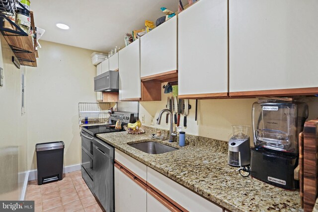 1413 Hopkins St NW, Washington, DC 20036 - kitchen featuring a sink, stainless steel appliances, white cabinets, light tile patterned flooring, and baseboards