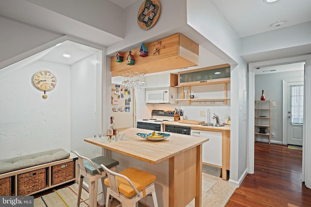 1413 Hopkins St NW, Washington, DC 20036 - kitchen with white appliances, a breakfast bar, butcher block countertops, white cabinetry, and recessed lighting