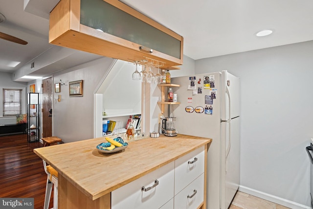 1413 Hopkins St NW, Washington, DC 20036 - kitchen with wooden counters, white cabinetry, freestanding refrigerator, wood finished floors, and baseboards