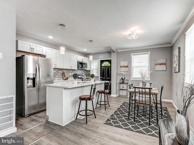 3812 Midheights Rd, Baltimore, MD 21215 - kitchen with stainless steel appliances, an island with sink, decorative backsplash, a kitchen bar, and light countertops