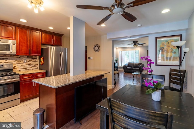 8627 Gilbert St, Philadelphia, PA 19150 - kitchen featuring stainless steel appliances, ceiling fan, tasteful backsplash, light stone counters, and recessed lighting