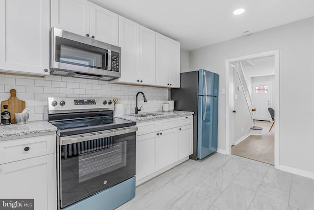 2839 Winton St, Philadelphia, PA 19145 - kitchen featuring stainless steel appliances, a sink, baseboards, white cabinetry, and tasteful backsplash