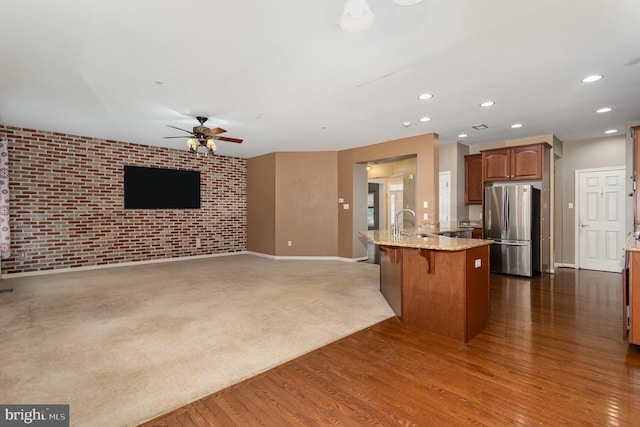 168 Joshua Dr, Hanover, PA 17331 - kitchen featuring freestanding refrigerator, a ceiling fan, brick wall, light stone countertops, and a kitchen bar