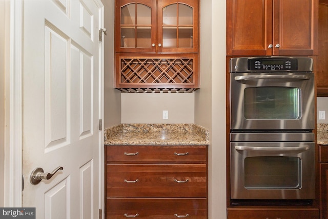 168 Joshua Dr, Hanover, PA 17331 - kitchen with stainless steel double oven, glass insert cabinets, light stone countertops, and brown cabinetry