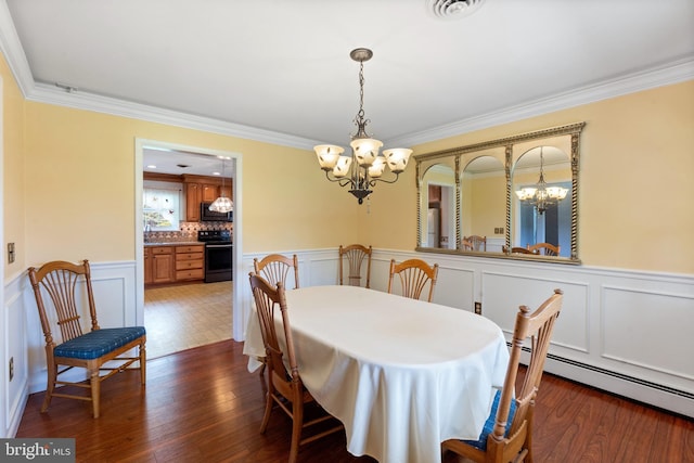 1404 Stockton Rd, Joppa, MD 21085 - dining room featuring a chandelier, a baseboard heating unit, ornamental molding, a wainscoted wall, and a decorative wall