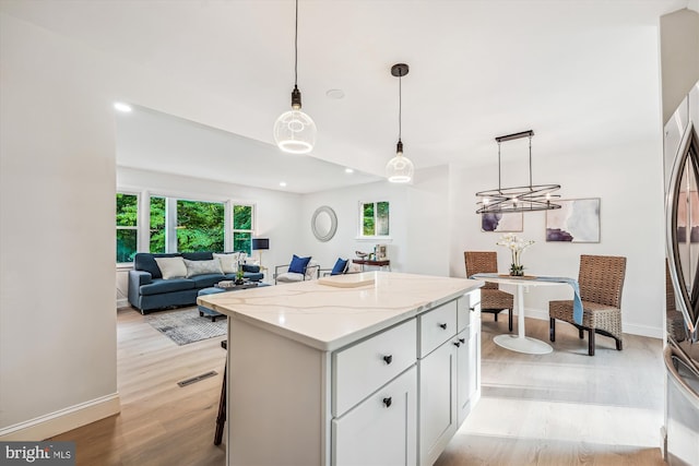 5202 Bayne Pl, Temple Hills, MD 20748 - kitchen featuring light wood-style floors, white cabinets, a center island, light stone countertops, and hanging light fixtures