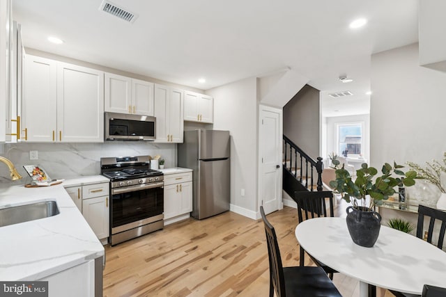 344 Elm St NW, Washington, DC 20001 - kitchen with appliances with stainless steel finishes, a sink, light wood-style flooring, backsplash, and light stone counters