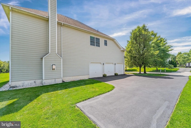 915 Mather Dr, Bear, DE 19701 - view of side of property with an attached garage, asphalt driveway, a chimney, and a yard