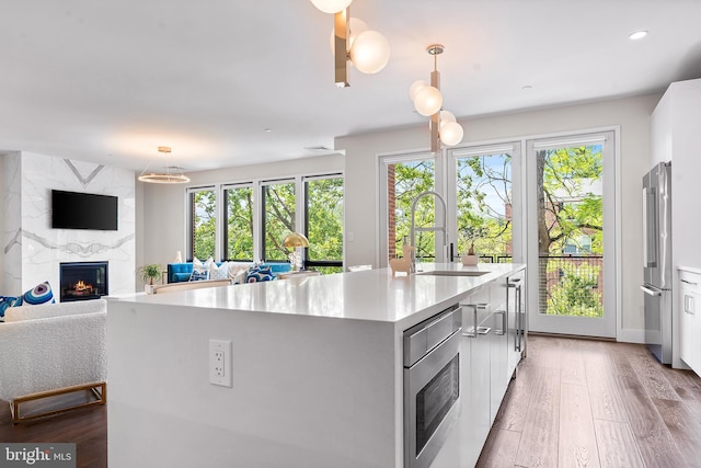 427 E Lancaster Ave Unit 1202, Wayne, PA 19087 - kitchen featuring a premium fireplace, open floor plan, appliances with stainless steel finishes, white cabinets, and an island with sink