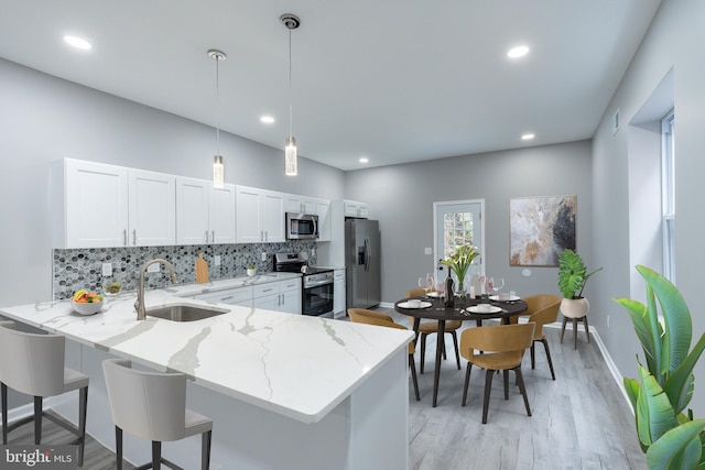 5229 Webster St, Philadelphia, PA 19143 - kitchen featuring appliances with stainless steel finishes, a sink, decorative backsplash, light wood finished floors, and light stone countertops