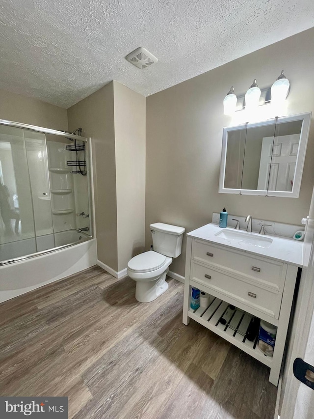 25795 Shamrock Ln, Mechanicsville, MD 20659 - full bathroom featuring wood finished floors, toilet, vanity, bath / shower combo with glass door, and a textured ceiling