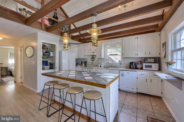402 Swamp Rd, Morgantown, PA 19543 - kitchen featuring white appliances, tile counters, white cabinets, a center island, and beam ceiling