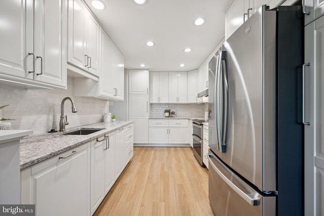 5071 Columbia Rd, Columbia, MD 21044 - kitchen with stainless steel appliances, a sink, light wood-style floors, white cabinets, and decorative backsplash