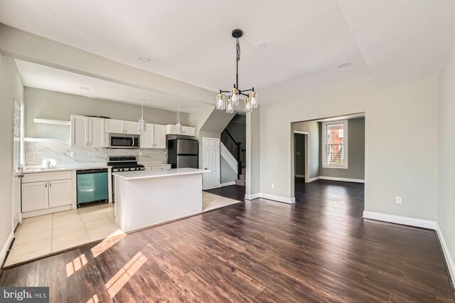 3711 Spaulding Ave, Baltimore, MD 21215 - kitchen featuring stainless steel appliances, white cabinets, backsplash, light countertops, and light wood-style floors