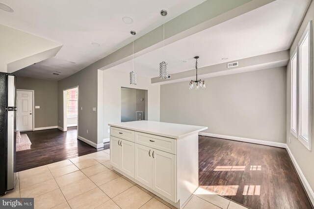 3711 Spaulding Ave, Baltimore, MD 21215 - kitchen with freestanding refrigerator, light tile patterned flooring, white cabinets, decorative light fixtures, and baseboards