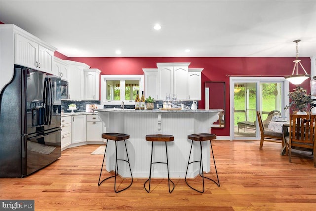 10840 Wolfsville Rd, Myersville, MD 21773 - kitchen with black refrigerator with ice dispenser, white cabinets, backsplash, a breakfast bar area, and light wood-style floors