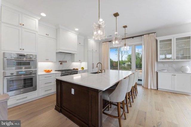 1632 Chain Bridge Rd, Mclean, VA 22101 - kitchen with a chandelier, a sink, stainless steel appliances, white cabinetry, and light wood-type flooring