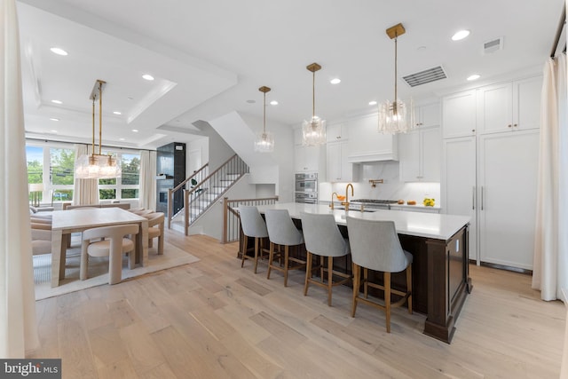 1632 Chain Bridge Rd, Mclean, VA 22101 - kitchen with a chandelier, light wood-type flooring, light countertops, double oven, and a tray ceiling