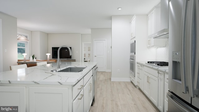 23640 Bolton Crescent Ter Unit 13-306, Ashburn, VA 20148 - kitchen with stainless steel appliances, a sink, wall chimney range hood, a kitchen island with sink, and light wood-style flooring