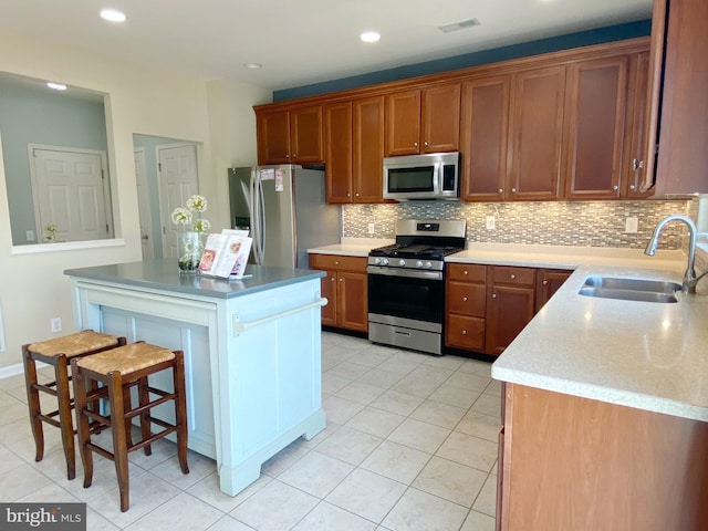 614 Empire Dr, Downingtown, PA 19335 - kitchen featuring appliances with stainless steel finishes, a sink, decorative backsplash, a kitchen island, and a kitchen bar