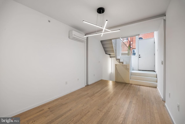 2710 W Harper St, Philadelphia, PA 19130 - unfurnished living room with a wall unit AC, light wood-style floors, stairway, and a chandelier