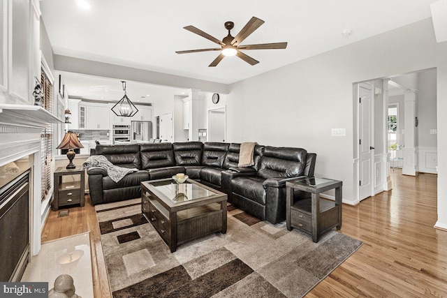 202 Galyn Dr, Brunswick, MD 21758 - living room with decorative columns, a premium fireplace, ceiling fan, light wood finished floors, and a chandelier