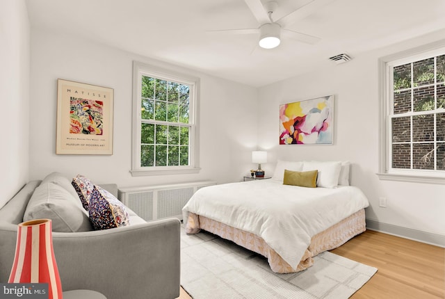 3520 28th St NE, Washington, DC 20018 - bedroom with radiator heating unit, wood finished floors, multiple windows, and ceiling fan
