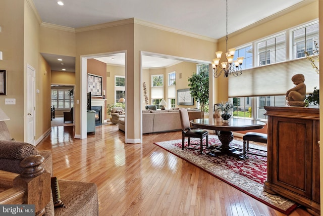 6 Easton Ln, Cinnaminson, NJ 08077 - dining space featuring light wood-type flooring, a chandelier, plenty of natural light, a lit fireplace, and ornamental molding