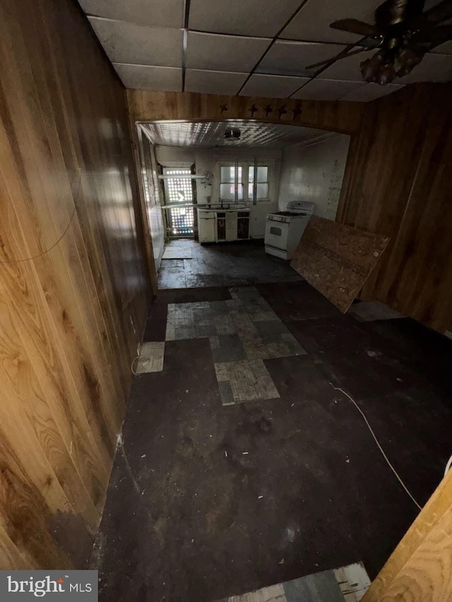 1902 Ramsay St, Baltimore, MD 21223 - unfurnished living room featuring wooden walls, a ceiling fan, and a drop ceiling