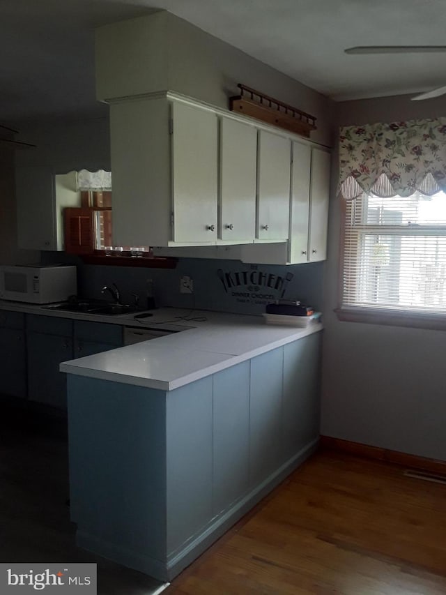28 Kough Rd, Newville, PA 17241 - kitchen featuring white microwave, a peninsula, wood finished floors, light countertops, and white cabinetry