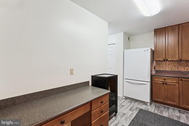 9039 Sligo Creek Pkwy Unit 102, Silver Spring, MD 20901 - kitchen with freestanding refrigerator, dark countertops, beverage cooler, tasteful backsplash, and brown cabinetry