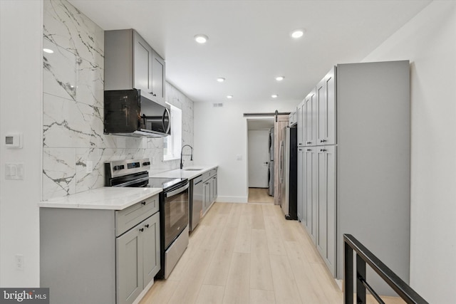 1910 E Atlantic St, Philadelphia, PA 19134 - kitchen with appliances with stainless steel finishes, gray cabinetry, a barn door, tasteful backsplash, and recessed lighting
