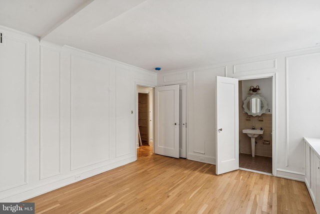 1901 Walnut St Unit 16E, Philadelphia, PA 19103 - unfurnished bedroom with a decorative wall, light wood-style flooring, and connected bathroom