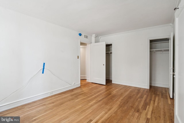 1901 Walnut St Unit 16E, Philadelphia, PA 19103 - unfurnished bedroom featuring two closets, wood finished floors, crown molding, and baseboards
