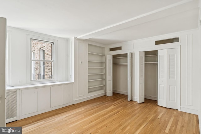 1901 Walnut St Unit 16E, Philadelphia, PA 19103 - unfurnished bedroom with light wood-style flooring, two closets, and a decorative wall