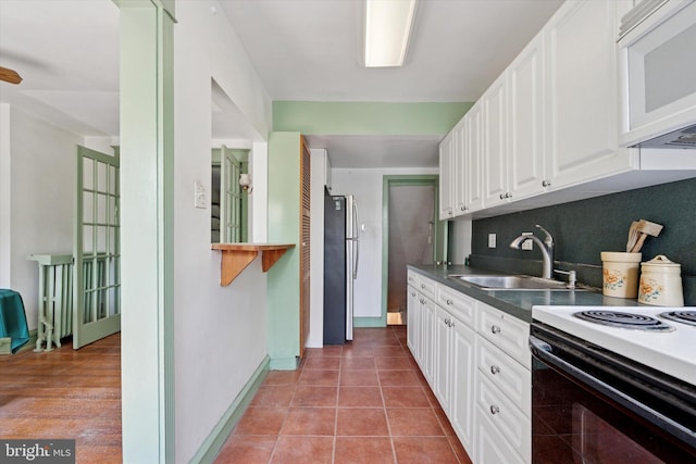 340 W Durham St, Philadelphia, PA 19119 - kitchen with freestanding refrigerator, white microwave, a sink, white cabinets, and range with electric cooktop