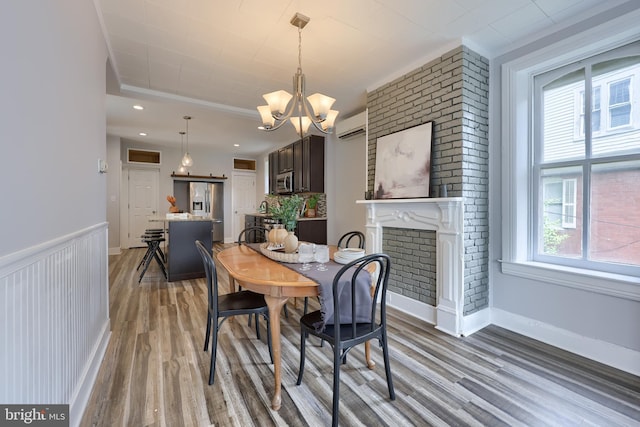 143 Hanover St, Glen Rock, PA 17327 - dining area with wood finished floors, a chandelier, crown molding, a wall unit AC, and a fireplace