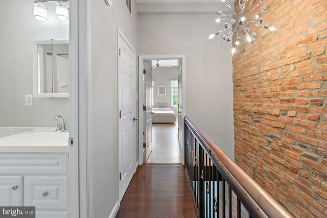 816 S Milton Ave, Baltimore, MD 21224 - hall featuring a sink, brick wall, a chandelier, and dark wood-style floors