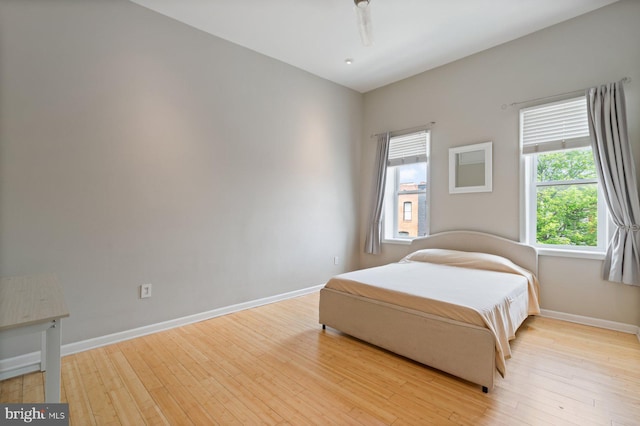 816 S Milton Ave, Baltimore, MD 21224 - bedroom featuring multiple windows, wood finished floors, and baseboards