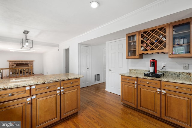 8321 Terra Grande Ave, Springfield, VA 22153 - kitchen with brown cabinetry, dark wood finished floors, light stone counters, ornamental molding, and glass insert cabinets
