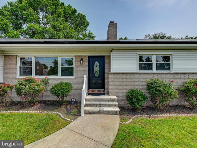 2411 Ruth Ave, Sparrows Point, MD 21219 - view of front of home with brick siding, a chimney, and roof mounted solar panels