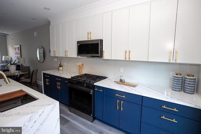 2127 Sigel St, Philadelphia, PA 19145 - kitchen featuring stainless steel microwave, black gas stove, blue cabinetry, white cabinetry, and light wood-style floors