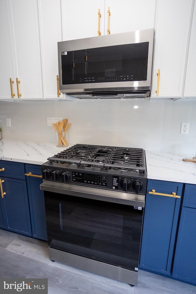 2127 Sigel St, Philadelphia, PA 19145 - kitchen with range with gas stovetop, blue cabinetry, stainless steel microwave, and white cabinets