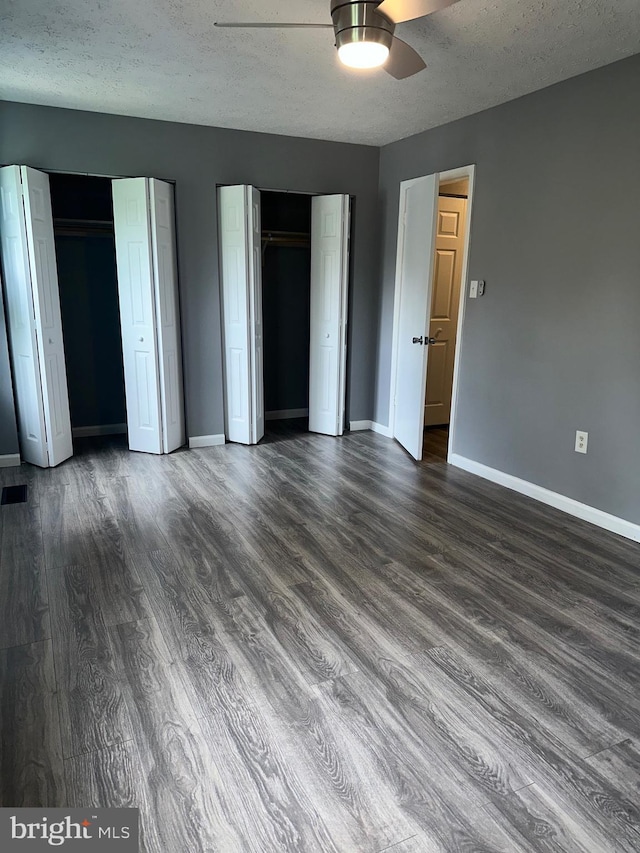 11429 Honeysuckle Ct Unit 3-3, Upper Marlboro, MD 20774 - unfurnished bedroom featuring dark wood-style flooring, baseboards, a textured ceiling, two closets, and a ceiling fan