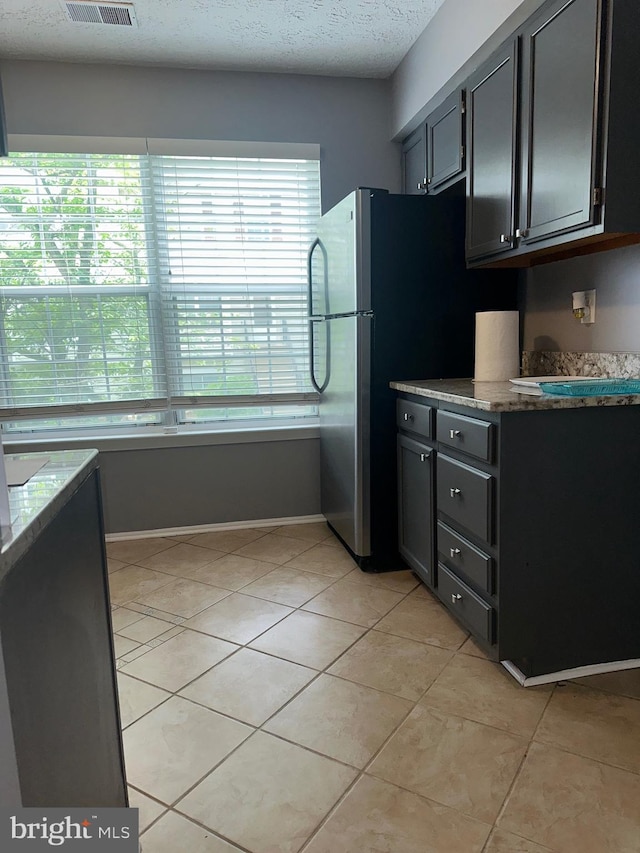 11429 Honeysuckle Ct Unit 3-3, Upper Marlboro, MD 20774 - kitchen featuring light tile patterned floors, freestanding refrigerator, light stone countertops, baseboards, and a textured ceiling