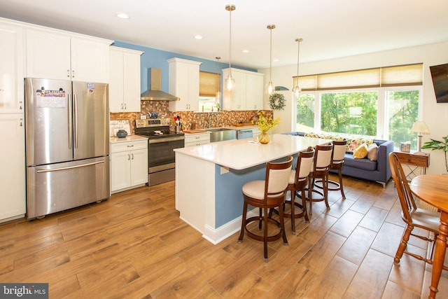 312 E 7th Ave, Trappe, PA 19426 - kitchen with appliances with stainless steel finishes, wall chimney exhaust hood, white cabinets, a kitchen breakfast bar, and a center island